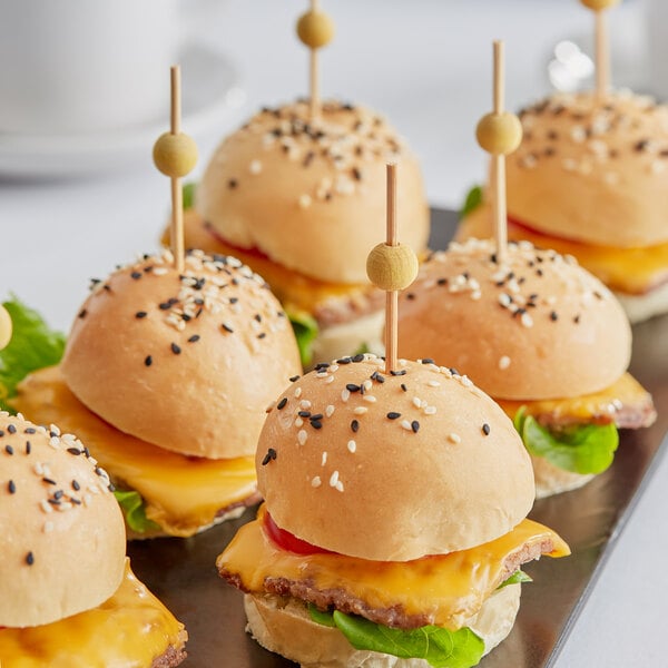 A tray of mini burgers with yellow bamboo ball picks.