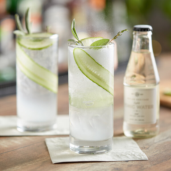 A glass of Boylan Tonic Water with cucumber slices and a sprig of leaves next to a bottle of Boylan Tonic Water.