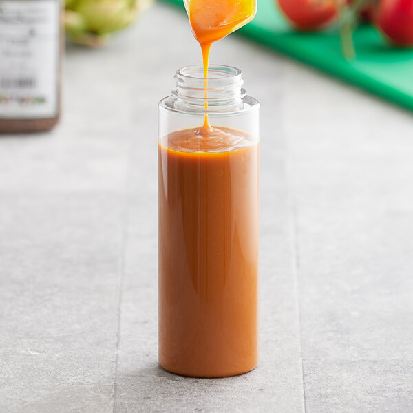A spoon pouring sauce into a clear PET sauce bottle.