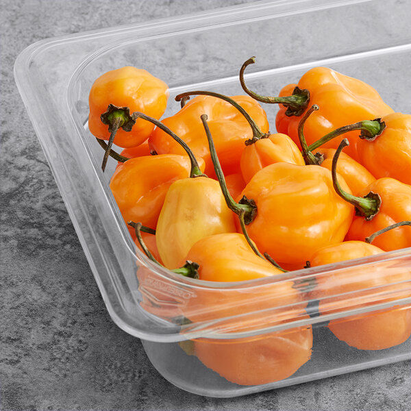 A plastic container filled with orange Fresh Orange Habanero Peppers.