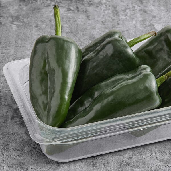 A plastic container of fresh poblano peppers.