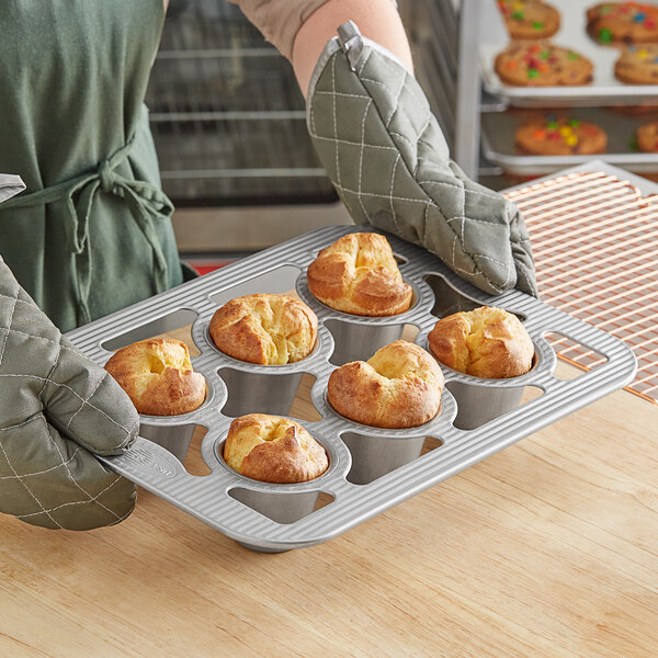 A person holding a Chicago Metallic popover pan with muffins.