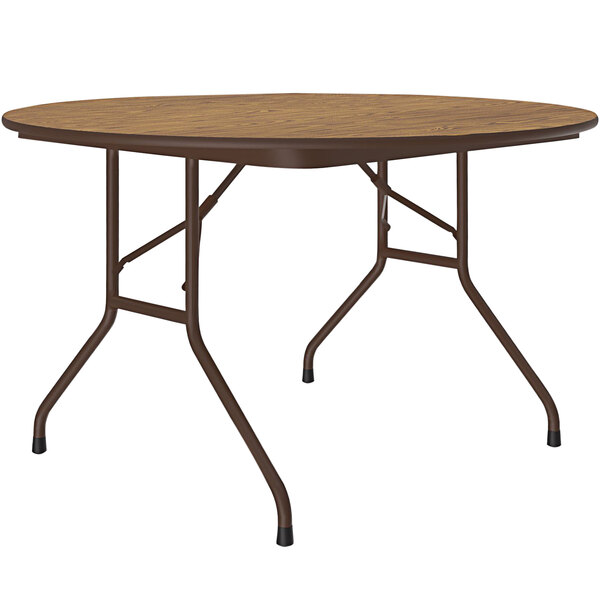 A Correll round folding table with a medium oak wood surface and a brown metal frame.