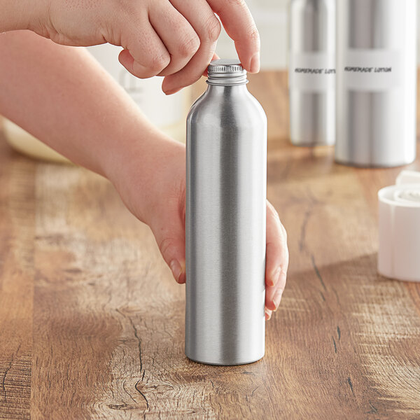 A person holding a silver aluminum bottle with a lid.