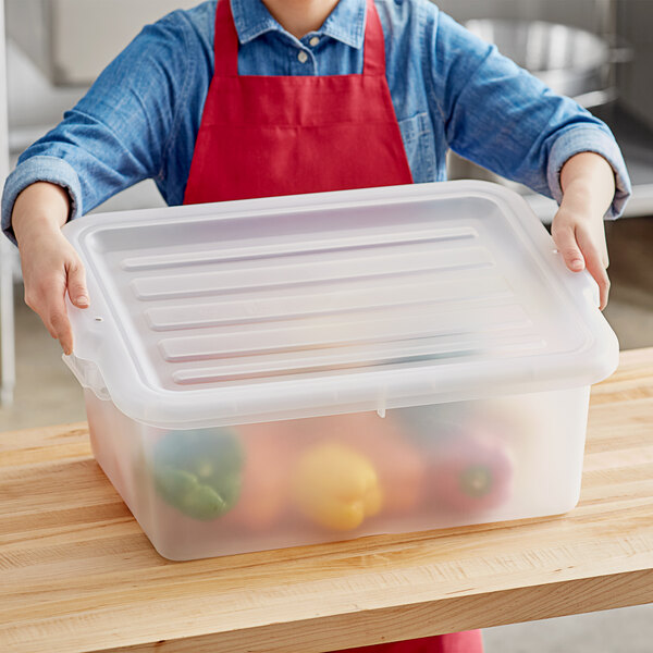A person holding a Vigor clear plastic lid over a container of vegetables.