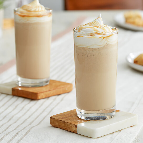 Two glasses of Barista Fria Caramel Lattes with whipped cream and caramel on top.