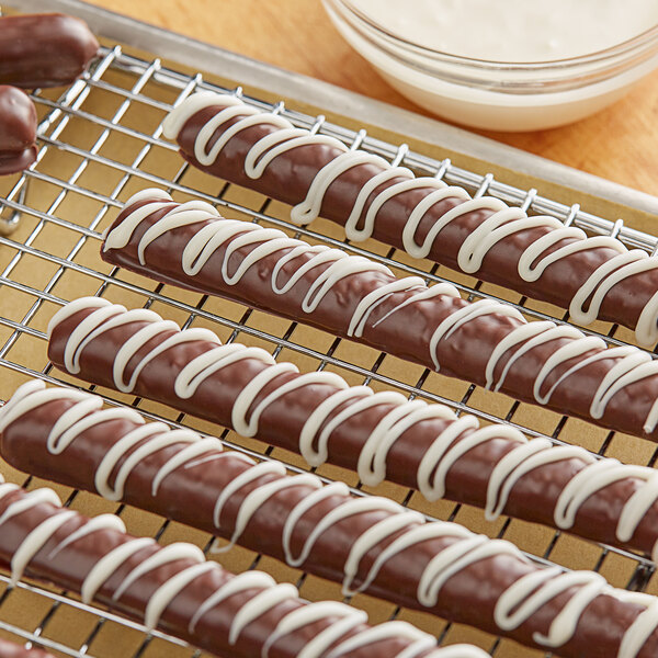 Chocolate covered pretzels made with Regal Foods white coating wafers on a cooling rack.