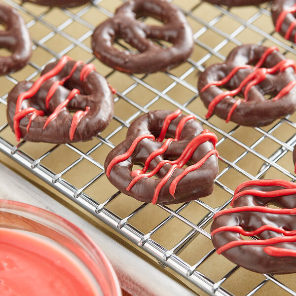 Chocolate covered pretzels with Regal Foods Red Vanilla Coating on a cooling rack.