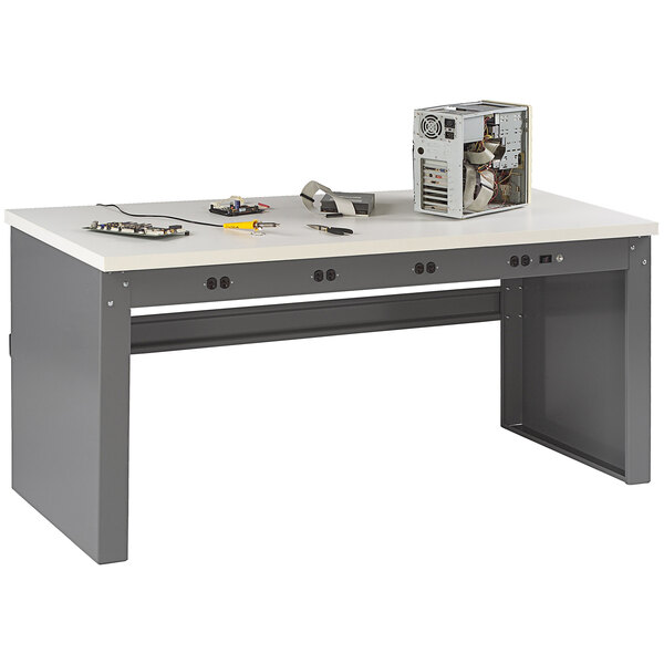 A white Tennsco workbench with a rectangular object and electrical equipment on it.