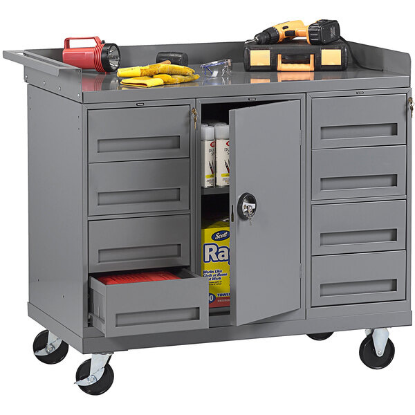 A grey Tennsco mobile workbench with tools on top.