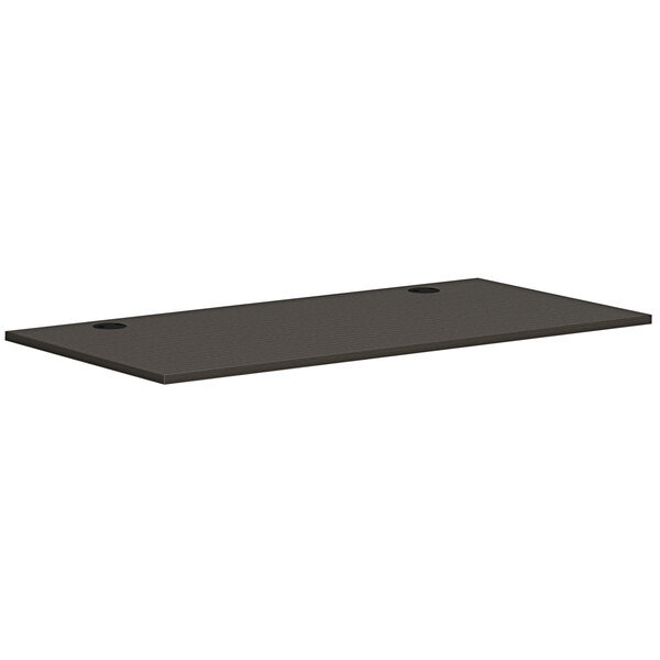 A rectangular slate teak worksurface with two holes in a black table.