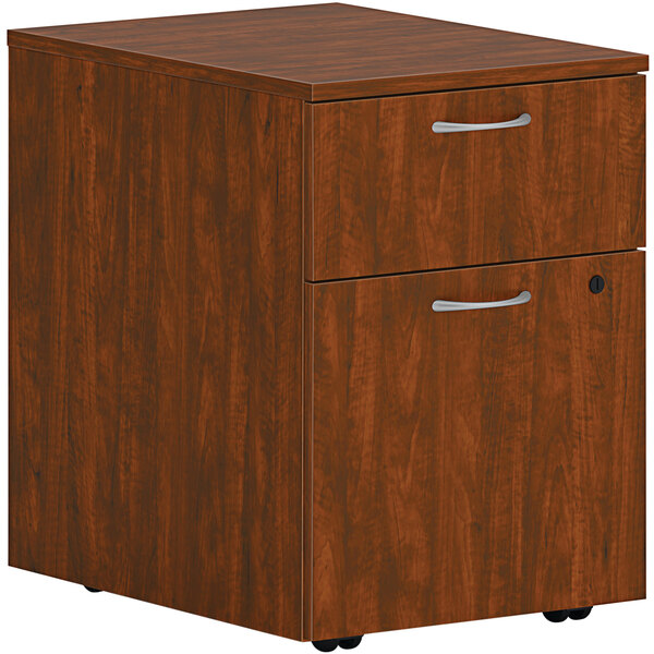 A HON russet cherry wooden file cabinet with a drawer.