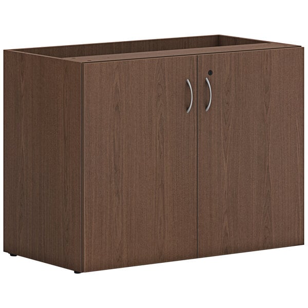 A brown HON storage cabinet with two doors and two drawers with silver handles.