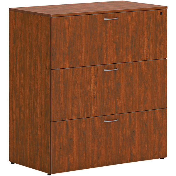 A HON russet cherry wooden lateral file cabinet with 3 drawers.