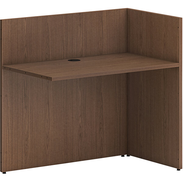 A brown wooden HON reception desk return shell with a shelf.