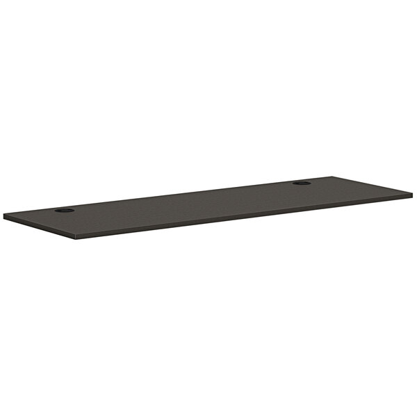 A black rectangular HON worksurface with two holes.