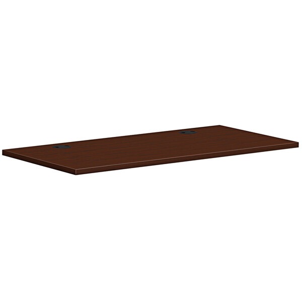 A brown rectangular HON worksurface with black holes.