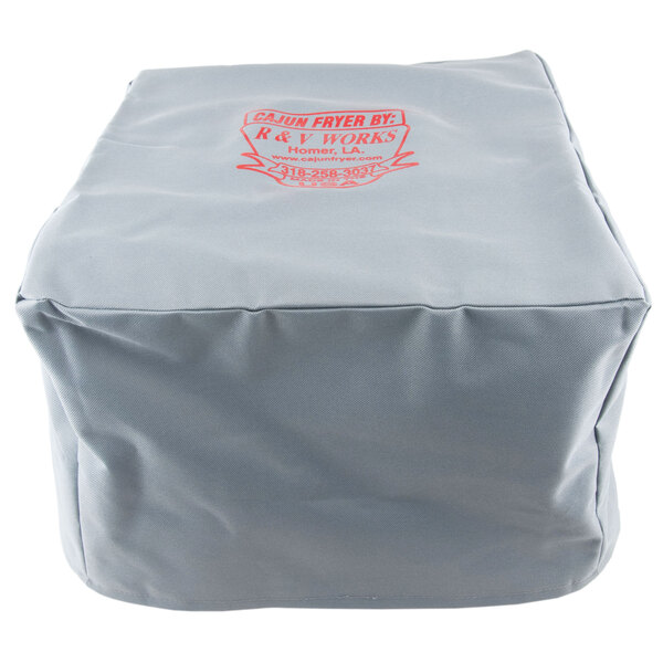 A grey canvas cover for an R & V Works Cajun deep fryer with a red and white logo.