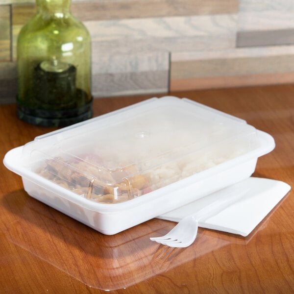 A Pactiv white rectangular plastic container with food inside and a clear lid.