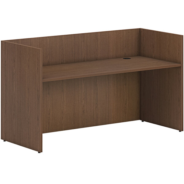 A brown HON reception desk shell with a shelf.