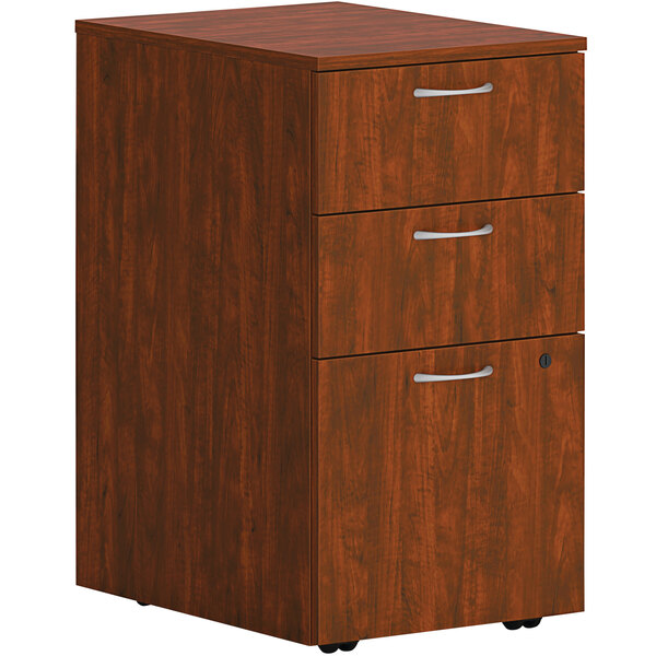 A russet cherry wooden mobile pedestal with 2 box drawers and 1 file drawer on wheels.