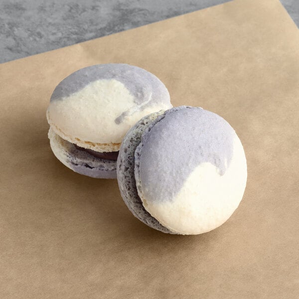 Two Macaron Centrale chocolate espresso caramel macarons on brown paper.