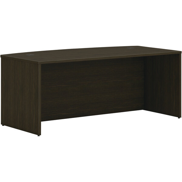 A brown HON Mod bow front desk with a dark finish.