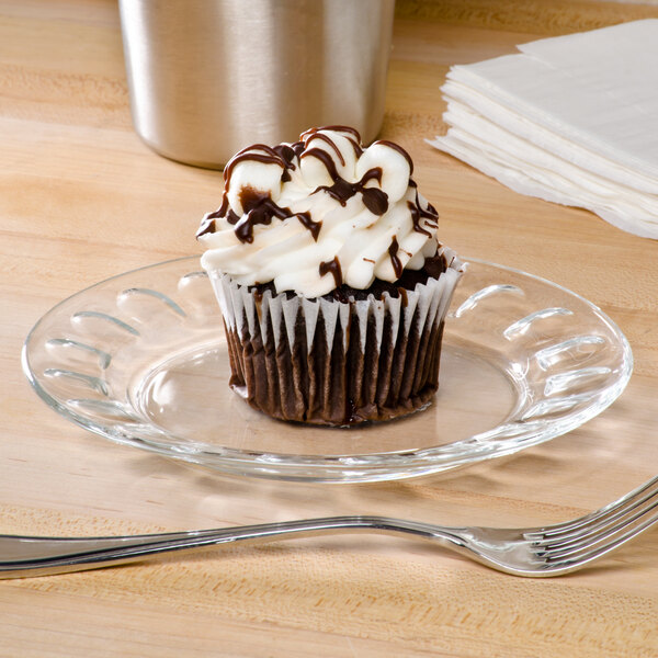 An Arcoroc glass dessert plate with a chocolate cupcake and a spoon.