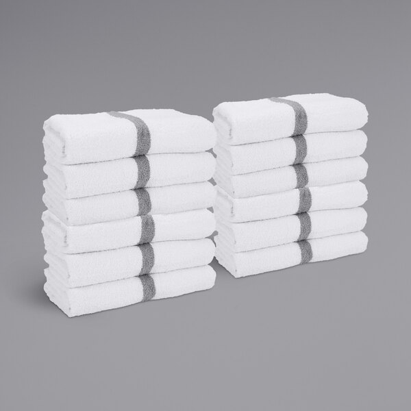 A stack of white Monarch Brands gym towels with a gray center stripe.