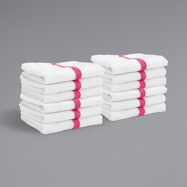 A stack of white Monarch Brands hand towels with pink center stripes.