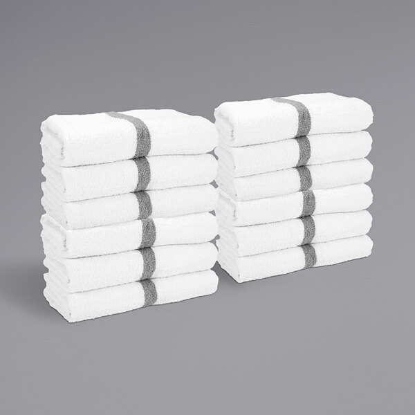 A stack of white Monarch Brands gym towels with gray center stripes.