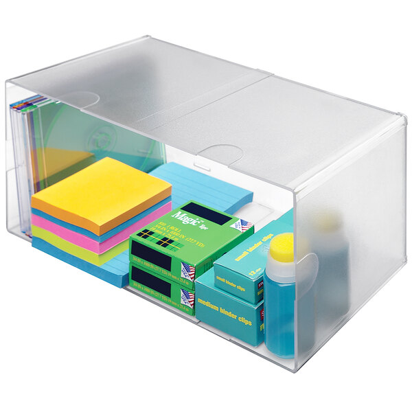 A clear plastic Deflecto stackable organizer cube with various items inside.