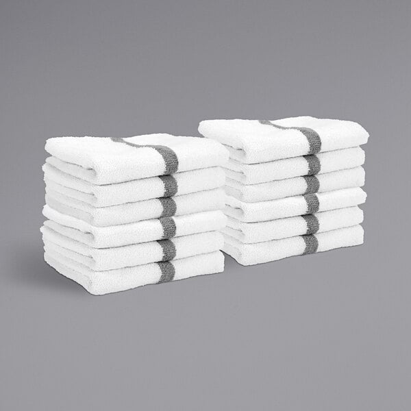 A stack of white Monarch Brands hand towels with a gray center stripe.