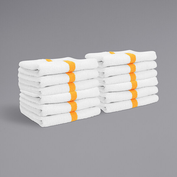 A stack of white Monarch Brands hand towels with gold center stripes.