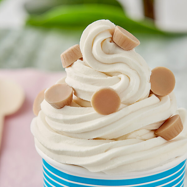 A cup of ice cream with Gertrude Hawk Mini Caramel Cups with caramel filling on top.