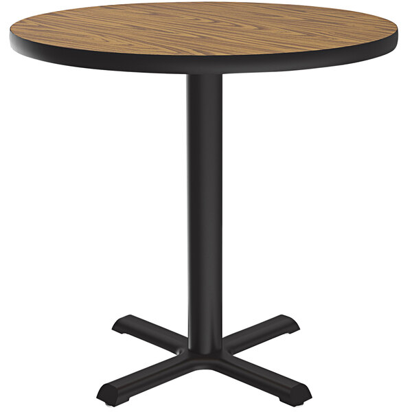 A Correll round table with a medium oak finish and a black base.