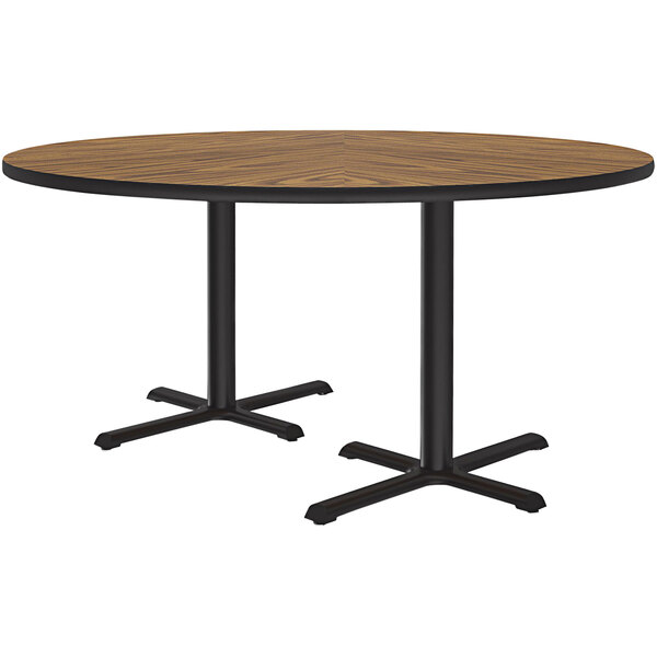 A Correll round table with a medium oak finish and two black cross bases.