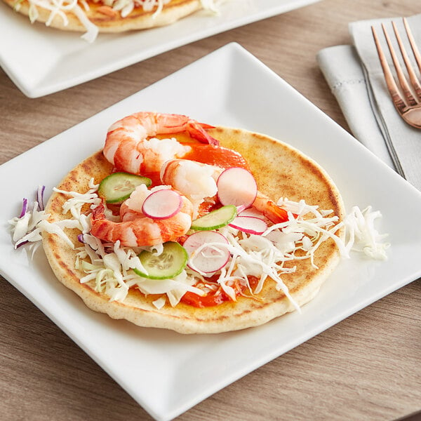 A plate with shrimp and vegetables on Grecian Delight New York Style White Pita Bread.