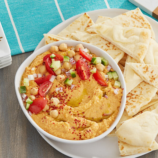 A bowl of Grecian Delight roasted red pepper hummus with vegetables and pita bread.
