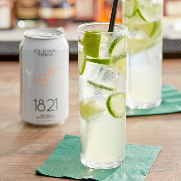 A glass of 18.21 Bitters Original Tonic with ice and lime slices on a table.