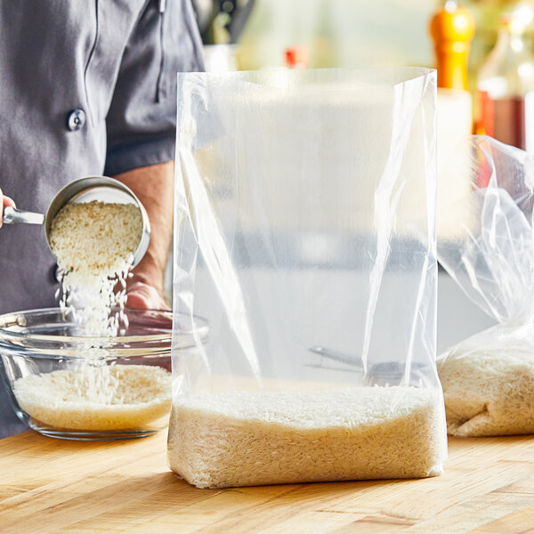 A person pouring rice into a clear plastic bag.