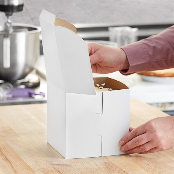 A person opening a white cake box.