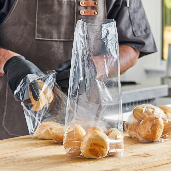 A person in gloves holding a Choice plastic bag of bread on a table.