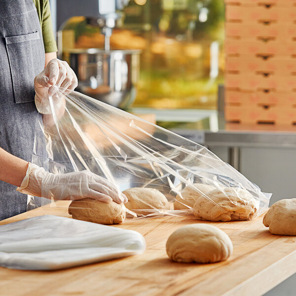 A person wearing gloves holding a Choice plastic bag over a ball of dough.