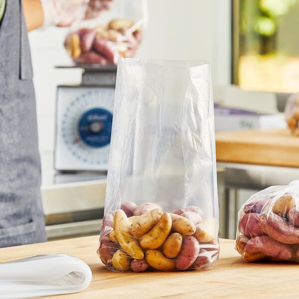 A person using a Choice extra heavy-duty plastic food bag to hold potatoes on a table.