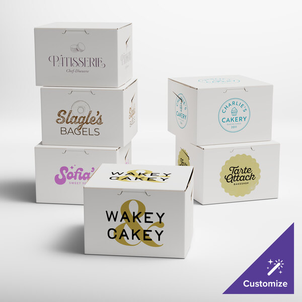 A group of white Baker's Lane cake boxes with purple, brown, and black text logos.