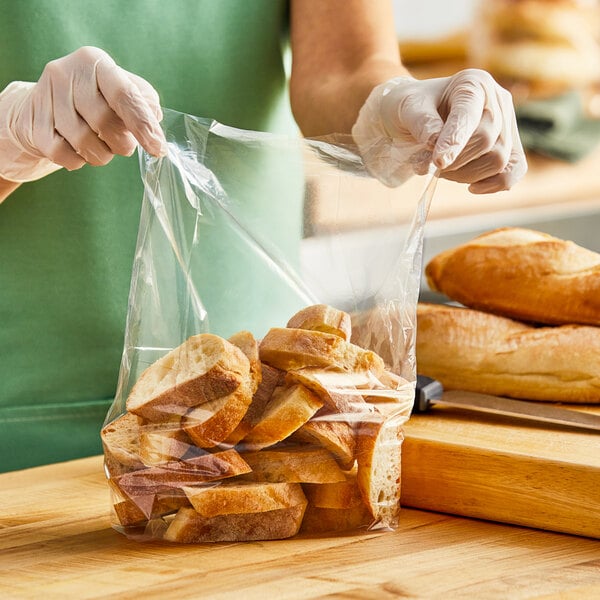 A woman in gloves putting a loaf of bread in a Choice plastic bag.
