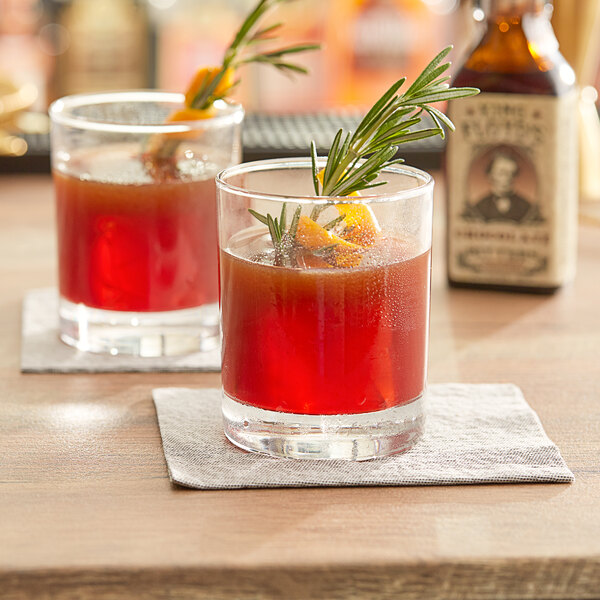 Two glasses of King Floyd's red drinks with an orange and rosemary sprig.