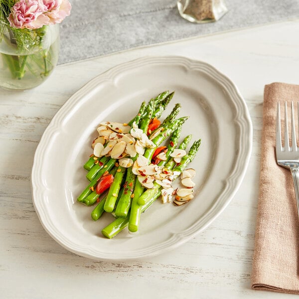 An Acopa warm gray scalloped porcelain platter with asparagus and almonds on it.