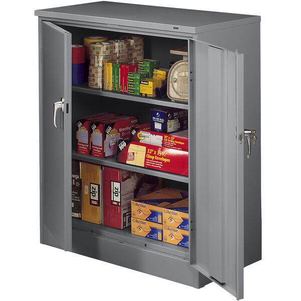 A dark gray Tennsco metal storage cabinet with solid doors filled with boxes and items.